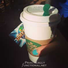 a person holding up a starbucks cup with a green frog on it