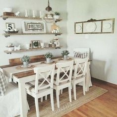 a dining room table with white chairs and shelves on the wall