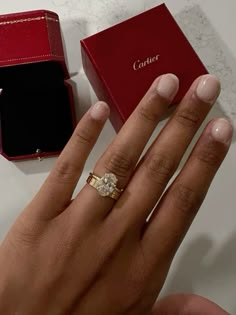 a woman's hand with an engagement ring in front of her and a box on the table