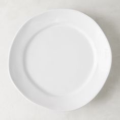 an empty white plate sitting on top of a table