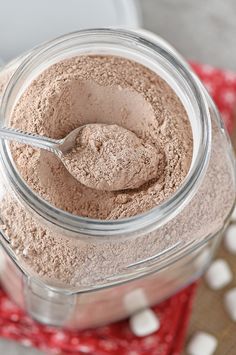 a spoon in a jar filled with some brown powder on top of a red and white towel