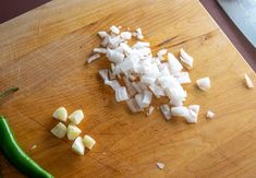 chopped onions and green peppers on a cutting board next to a knife with a pepper