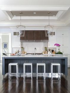 a kitchen island with stools in front of it and lights hanging from the ceiling