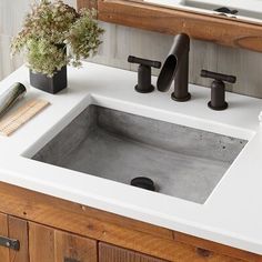 a bathroom sink sitting under a mirror next to a wooden counter top with two black faucets