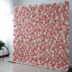 a large pink and white flowered wall in an empty room with a potted plant