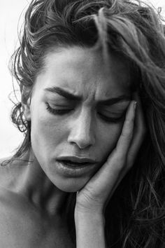 black and white photograph of a woman holding her hand to her face while looking down