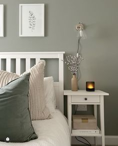 a white bed topped with pillows next to a night stand