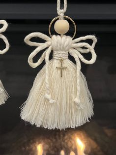 an angel ornament hanging from a string on a fireplace mantel with lit candles in the background