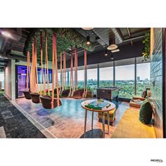 an office with large windows and lots of plants on the walls, along with seating