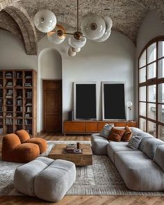 a living room filled with lots of furniture next to a large window covered in bookshelves