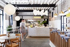 the interior of a restaurant with wooden tables and chairs, white lights hanging from the ceiling