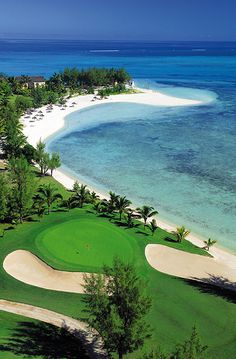 an aerial view of a golf course near the beach and ocean with palm trees in the foreground