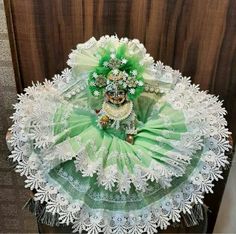 a green and white costume on display in front of a wooden door with lace around it