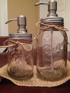 two mason jars with soap dispensers are sitting on a table