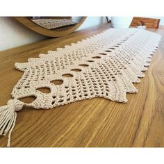 a crocheted table runner with tassels on the edge and a mirror in the background