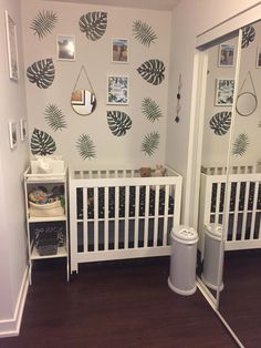 a baby's room with palm leaf wallpaper and white crib in the corner