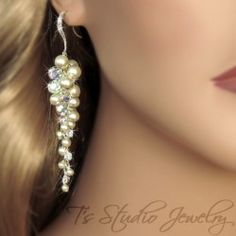 a close up of a woman's face wearing earrings with pearls and crystals on them