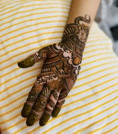 a woman's hand with hennap on her left arm and yellow striped shirt