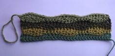 a close up of a knitted object on a purple surface with green and yellow stripes