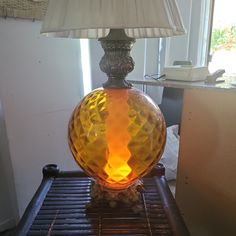 a lamp sitting on top of a metal table next to a glass vase with an orange liquid inside