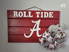 a wooden sign that says roll tide with a bow on it