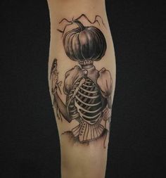 a woman's leg with a skeleton and pumpkin tattoo on her left calf sleeve