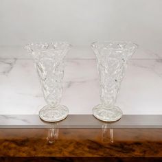 two clear vases sitting on top of a wooden table