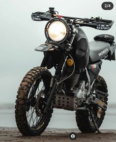 a black motorcycle parked on top of a sandy beach