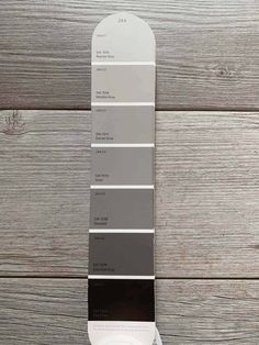 a pantone board with different shades of gray and white in it on a wooden surface