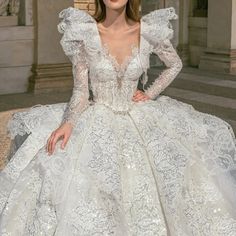 a woman in a white wedding dress sitting on the ground with her hands on her hips