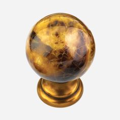 a golden colored marble ball on a gold metal base, against a white back ground