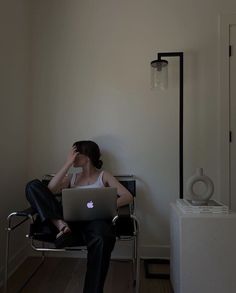 a woman sitting in a chair using a laptop computer