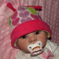 a baby wearing a pink hat and pacifier