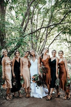 a group of women standing next to each other in front of some trees and bushes