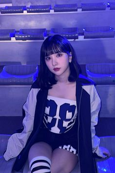 a woman sitting on the floor in front of some shelves with blue lights behind her