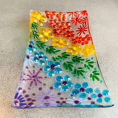 a multicolored glass plate with flowers and leaves on the bottom, sitting on a table