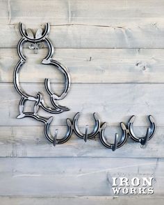 three metal hooks hang from the side of a wooden wall with an owl design on it