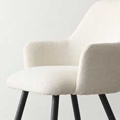 an upholstered white chair with black legs