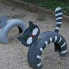 two black and white cats made out of tire rims sitting on the ground next to each other