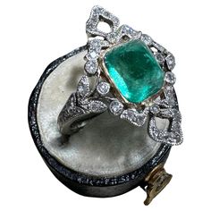 This enchanting early 20th-century ring centers on a glowing 4 carat sugarloaf emerald of Colombian origin, mounted in a gleaming yellow gold bezel. Measuring 7/8" in length, the emerald is and perfectly presented between glittering rose-cut diamond bows, nestled between shimmering split leaf shoulders that transition into a fluted shank. This delightful antique jewel has been hand fabricated in platinum and gold, with the emerald being a more recent addition. This ring is accompanied by a gemological report from GIA stating: Clarity enhanced (F2). Colombia - origin. Currently a ring size 6.5. Weight: 5.87 grams Measurements: 23 mm north to south Emerald: 8.30 x 6.45 x 9.03 mm, estimated 4 carats Notes: This ring is rather delicate as the emerald sits 3/8" off of the finger, please wear wi Rose Cut Diamond Pendant, Edwardian Diamond Ring, Antique Cocktail Ring, Diamond Bows, Platinum Diamond Rings, Large Necklace, Bow Ring, Colombian Emeralds, Emerald Pendant