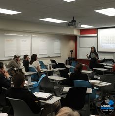 a group of people sitting at desks in front of a projector screen