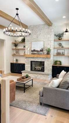 a living room filled with furniture and a fire place under a chandelier over a fireplace