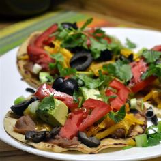 two tortillas topped with vegetables and black olives