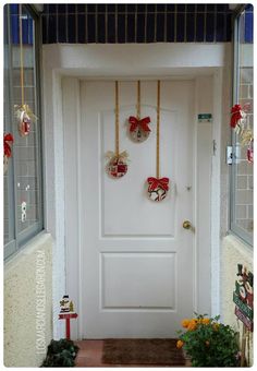 a white door with red bows hanging from it's sides and decorations on the side