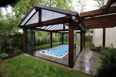 a hot tub in the middle of a backyard with a wooden gazebo and glass walls