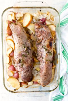 two meats and potatoes in a glass dish on a white table with green towel