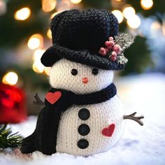 a knitted snowman with a black hat and scarf on it's head