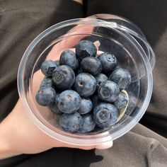 a person holding a plastic bowl filled with blueberries