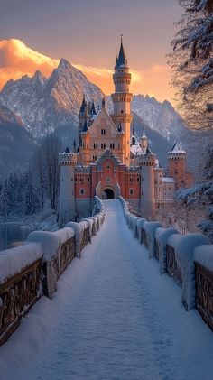 a snow covered walkway leading to a castle in the middle of winter with mountains in the background