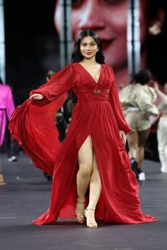 a woman in a red dress walks down the runway